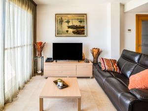 a living room with a black leather couch and a tv at Comfortable Apartment in L Eucaliptus with Swimming Pool in Deltebre