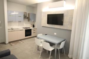 uma cozinha com uma mesa com cadeiras brancas e uma televisão em Persea mare appartamenti em Arma di Taggia