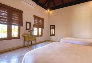 a bedroom with two beds and a table and windows at ileverde 82 - Garden villa in Punta Cana