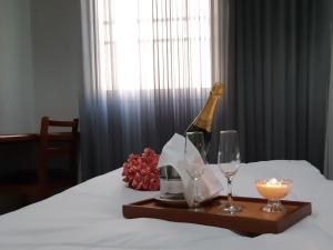 a bottle of champagne and two glasses on a bed at Hotel Executivo in Araguaína