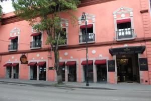 a pink building with red awnings on a street at Hotel Boutique Margarita Toluca in Toluca