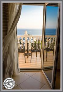 a balcony with a table and chairs and the ocean at Dorvin Apartments in Dhërmi