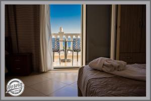 a bedroom with a bed and a view of a balcony at Dorvin Apartments in Dhërmi