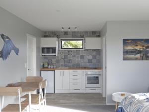 a kitchen with white cabinets and a table and a window at The Tui Studio - Te Anau Holiday Studio in Te Anau