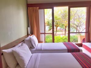 two beds in a hotel room with a window at Villa Vanna - Lombok in Senggigi 