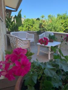 a patio with two chairs and a table and flowers at L'infinito Verde in Floridia