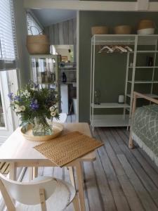 Una habitación con una mesa con un jarrón de flores. en Boutique zomerhuis De groene Parel, en Schoorl