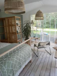 a bedroom with a bed and a chair and a table at Boutique zomerhuis De groene Parel in Schoorl