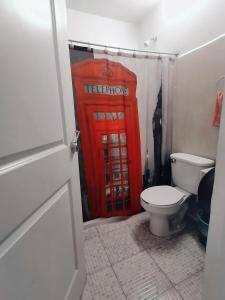 a red phone booth in a bathroom with a toilet at Hostal Maple in Querétaro