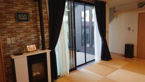 a living room with a fireplace and a glass door at Guesthouse Gifu SUAI in Gifu