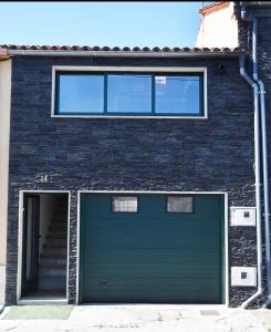 una puerta verde de garaje en un edificio de ladrillo en Casa da Ponte, en Monforte de Lemos