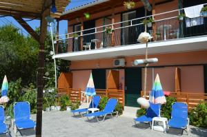 a group of chairs and umbrellas in front of a building at Billy's Rooms in Moraitika