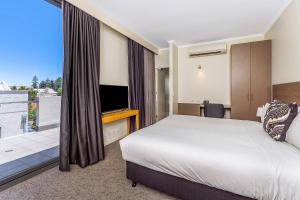 a hotel room with a bed and a television at Bannister 22 Hotel in Fremantle