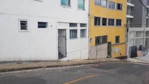 an empty street next to a white and yellow building at Estadia Confortável AP 102 in Juiz de Fora