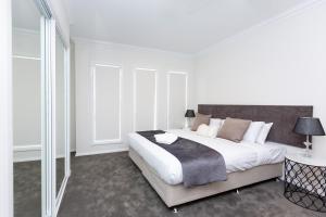 1 dormitorio blanco con 1 cama grande y ventanas en Wagga Apartments #3, en Wagga Wagga