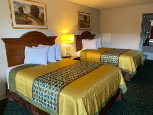 Dos camas en una habitación de hotel con sábanas amarillas. en Harrisonville Inn & Suites, en Harrisonville