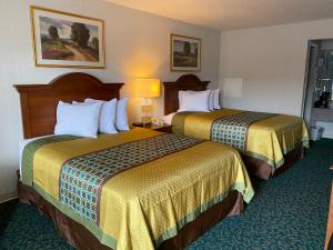 2 Betten in einem Hotelzimmer mit gelber Bettwäsche in der Unterkunft Harrisonville Inn & Suites in Harrisonville