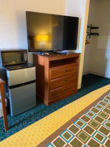 a flat screen tv sitting on top of a wooden dresser at Harrisonville Inn & Suites in Harrisonville