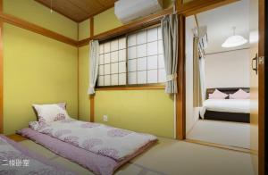 um pequeno quarto com uma cama e uma janela em 10mins train to Namba, 4 mins walk to stn, 2 floors japanese style , 2-8 people em Osaka