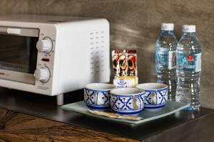 a tray with cups and bottles of water next to a microwave at Tisha Langkawi Wellness Resort in Pantai Cenang