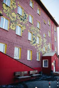 ein großes rotes Gebäude mit Bänken davor in der Unterkunft Matreshka Hotel in Irkutsk