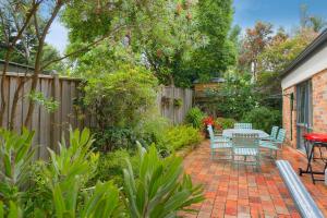 a patio with a table and chairs in a garden at Bungunyah Apartments in Croydon