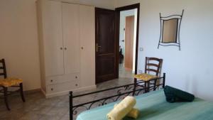een slaapkamer met een bed en 2 stoelen en een deur bij Sa Pira in Budoni