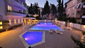 une grande piscine avec des chaises longues et un bâtiment dans l'établissement Ramira Joy Hotel, à Alanya