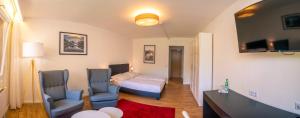 バート・ウーラッハにあるHotel Quellenhof Bad Urachのベッド1台、椅子2脚、テレビが備わる客室です。