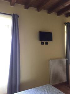 a bedroom with a tv on the wall and a curtain at Ababo Affittacamere in Quattro Castella