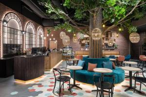 a lobby with a blue couch and tables and a tree at Original Sokos Hotel Kupittaa in Turku