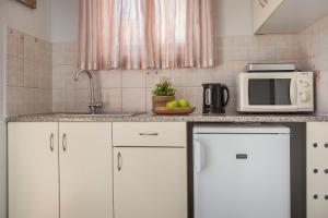 cocina con armarios blancos y microondas en Panorama Fanari studios and apartments en Argostoli