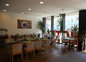 a restaurant with green tables and chairs and windows at Hotel Christl München Innenstadt in Munich