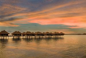 a group of huts on the water at sunset at Golden Palm Tree Sepang in Sepang