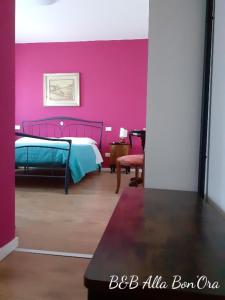 een slaapkamer met een bed en een roze muur bij B&B Alla Bon'ora in Volpago del Montello