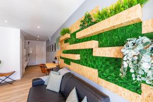 un salon avec un mur vert orné de plantes dans l'établissement Le XV d'Agen - Appart'Hôtel SPA - Clim - Melina & Alfred, à Agen