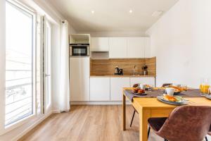 a kitchen with white cabinets and a table with food on it at Le XV d'Agen - Appart'Hôtel SPA - Clim - Melina & Alfred in Agen