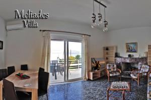 a living room with a table and chairs and a fireplace at Meliades Villa in Agioi Theodoroi