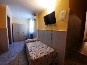 Habitación con 2 camas y TV en la pared. en Hostal Alba, en Albacete