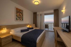 a hotel room with a bed and a desk with a television at Poseidon The Beach Hotel in Budva