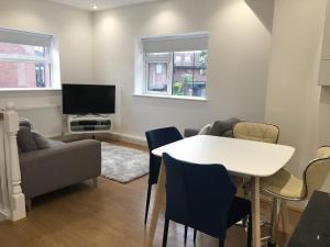 a living room with a table and a tv at Beautiful 1 BED Serviced APARTMENT COBHAM Town Centre in Cobham