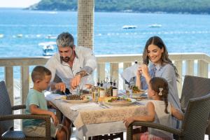 a family eating food at a table on the beach at Poseidon The Beach Hotel in Budva