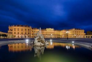 un bâtiment avec une fontaine devant lui la nuit dans l'établissement Continental Hotel-Pension, à Vienne