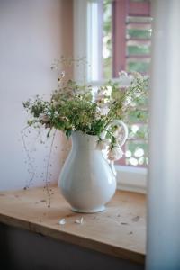 a white vase filled with flowers sitting on a table at Zum Riesen Historic Refugium in Laces