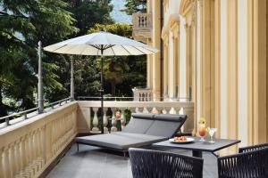 eine Terrasse mit einem Sonnenschirm, einem Tisch und Stühlen in der Unterkunft Grand Hotel Victoria concept & spa, by R Collection Hotels in Menaggio