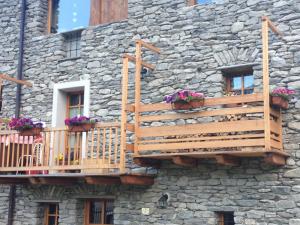 un edificio de piedra con dos cubiertas y flores en él en Bilocale pietra e legno immerso nella natura, en Morgex