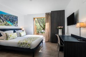 ラ・シオタにあるオテル コルニッシュ デュ リウケのベッドとデスクが備わるホテルルームです。
