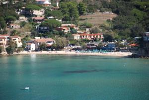 a boat in the water next to a beach at Hotel Danila in Portoferraio