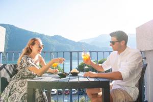 a man and woman sitting at a table with drinks at Park Hotel Abbadia in Abbadia Lariana