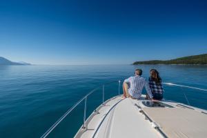 a couple sitting on the bow of a boat on the water at Poseidon The Beach Hotel in Budva